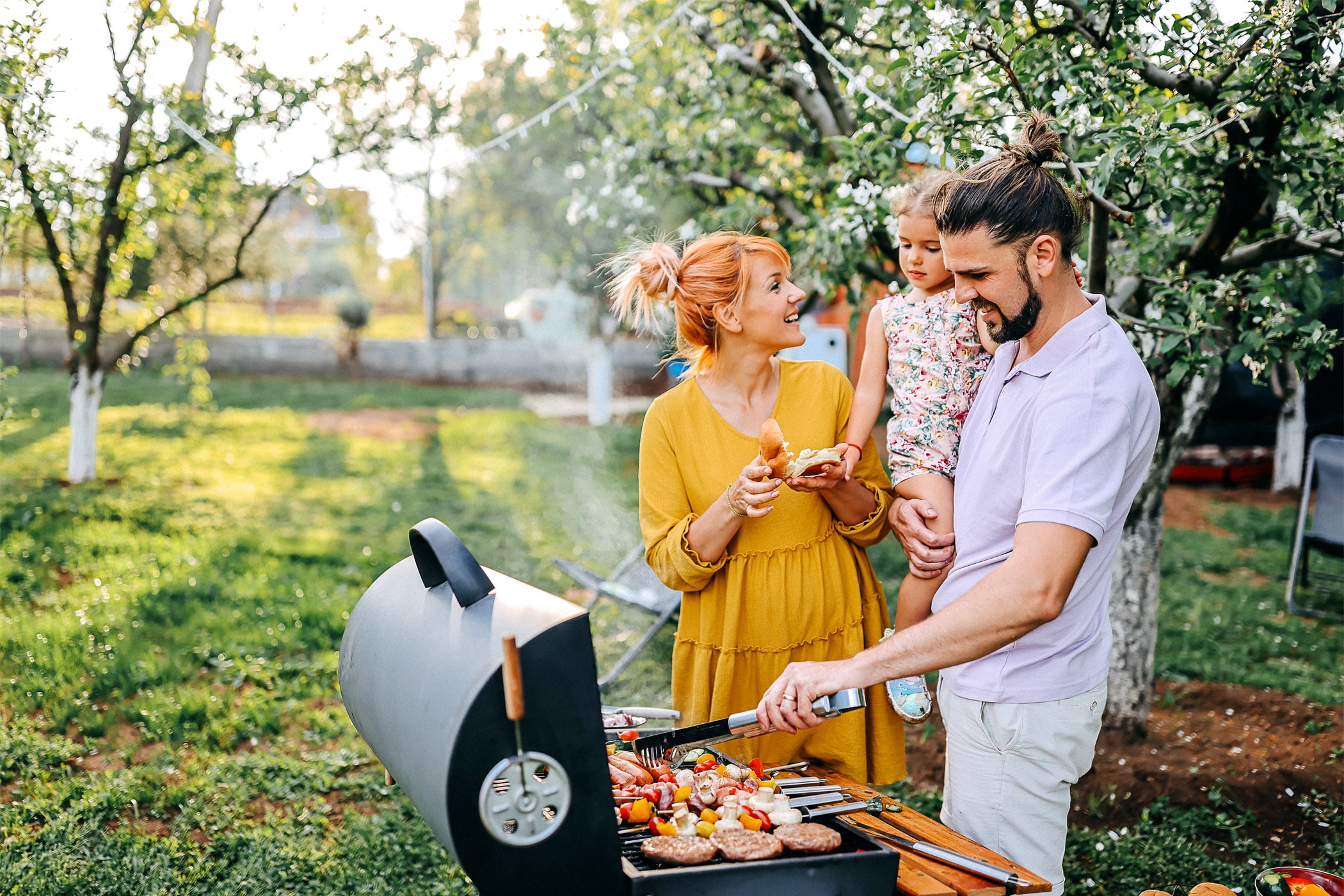 Family preparing meal in backyard on barbecue grill