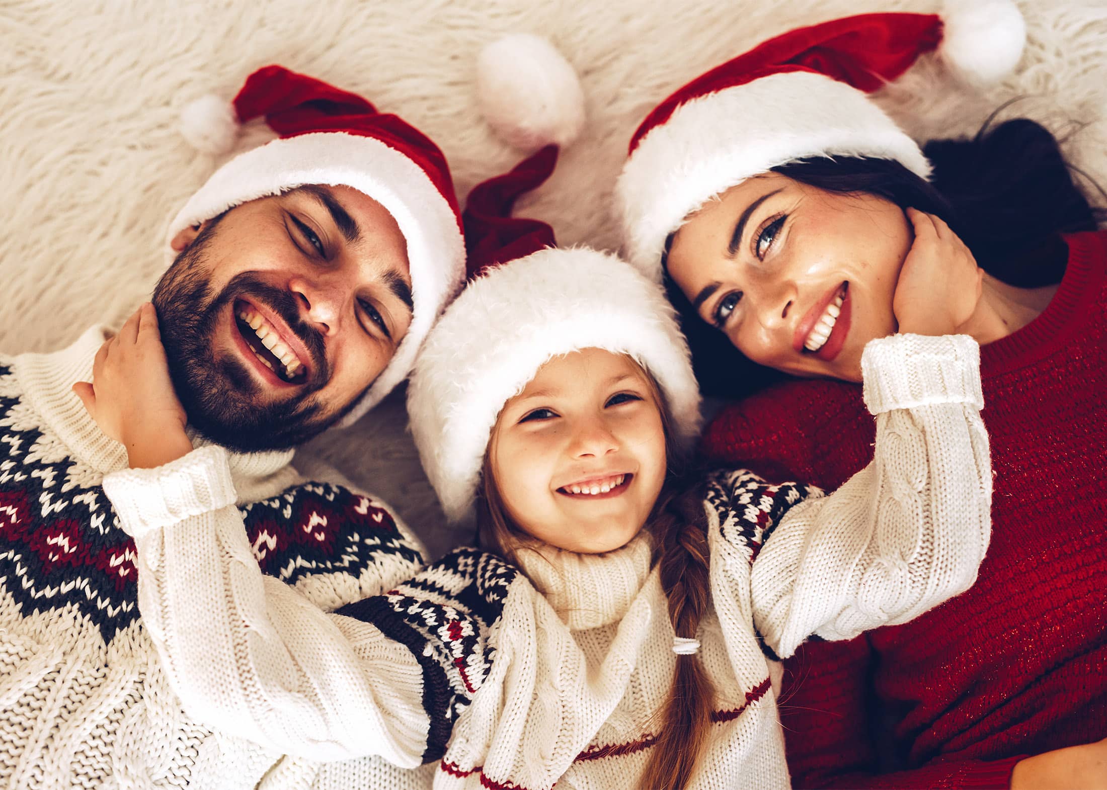 Christmas family! Happy mom,dad and little daughter on Santa Claus hats lying down. Enjoyng love hugs, holidays people. Togetherness concept