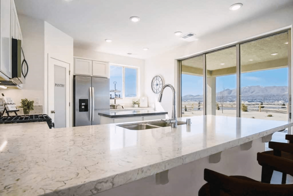 A kitchen with white marble countertops, designed by Jenuane.