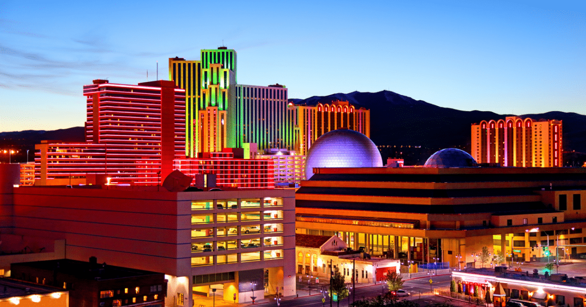 The city of Reno lit up in multiple colors against the blue evening sky.